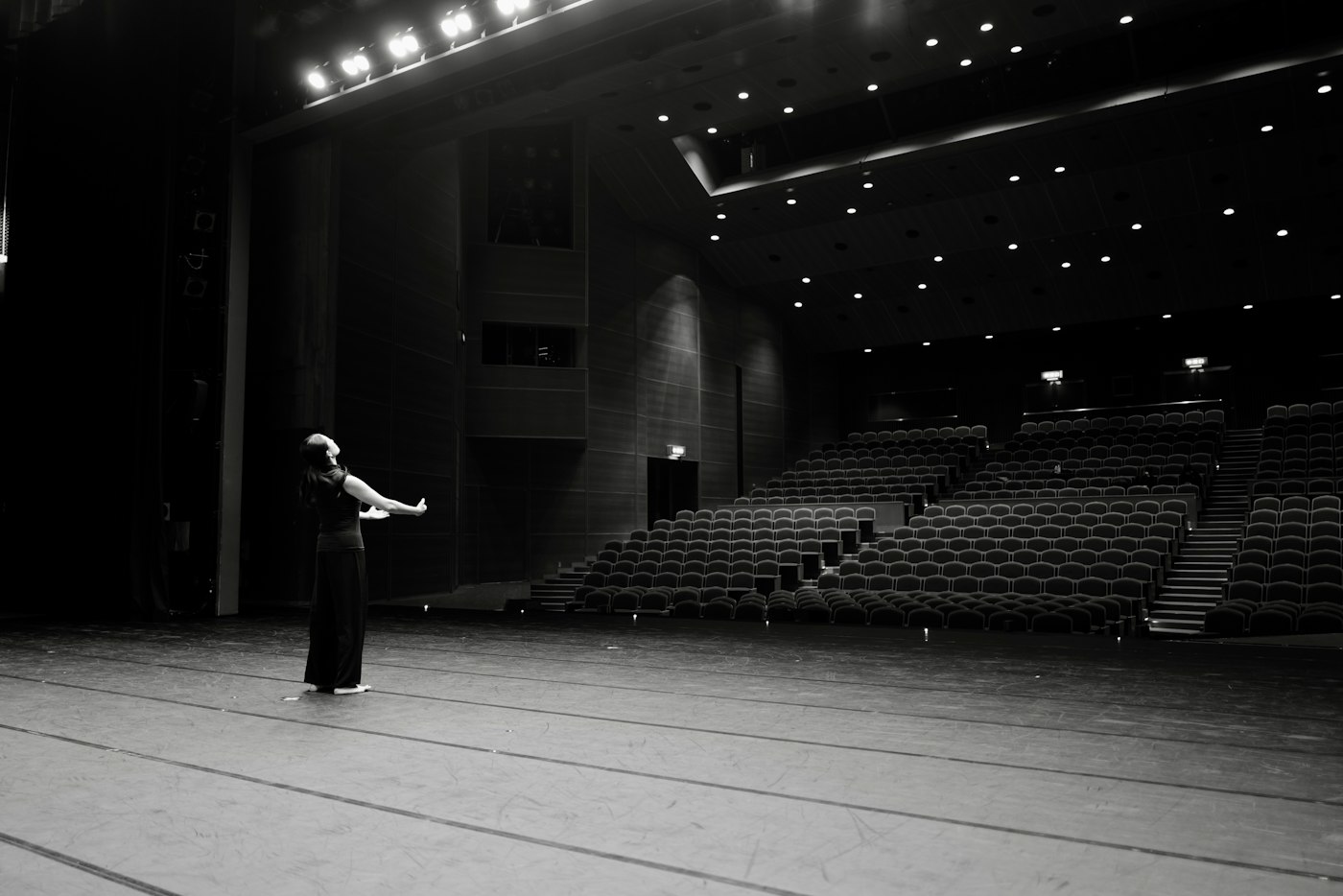 Tancerka ćwicząca samotnie na pustej scenie teatralnej